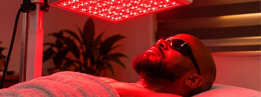 A client lying under red light panels wearing goggles